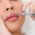 Close up of beautician hands in gloves injecting female lips with botox. Calm woman is lying with closed eyes
